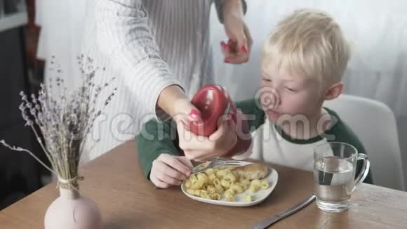 妈妈在她儿子的盘子里倒了番茄酱午餐时吃意大利面和肉丸视频的预览图
