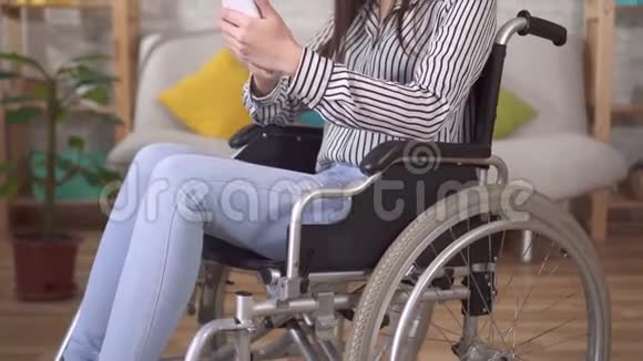 坐轮椅的年轻亚洲残疾妇女使用智能手机视频的预览图