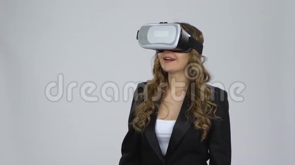 在演播室的灰色背景上戴着虚拟现实眼镜的女人视频的预览图