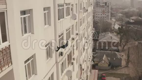 工业登山者拿着一束鲜花挂在公寓楼的绳子上小心翼翼地往下走危险视频的预览图