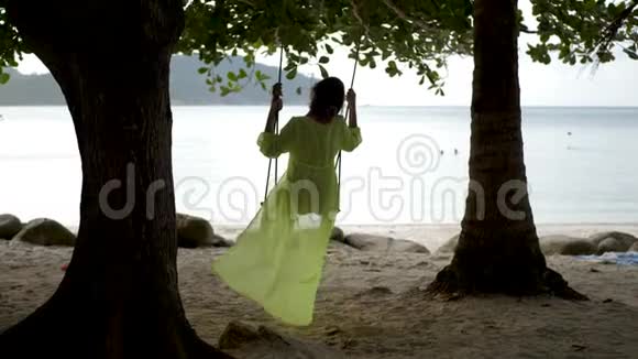 穿绿色帕雷奥秋千海滩的女人视频的预览图
