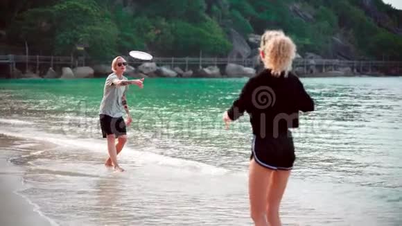 一个阳光明媚的日子两个年轻的女人在热带海滩扔飞盘视频的预览图