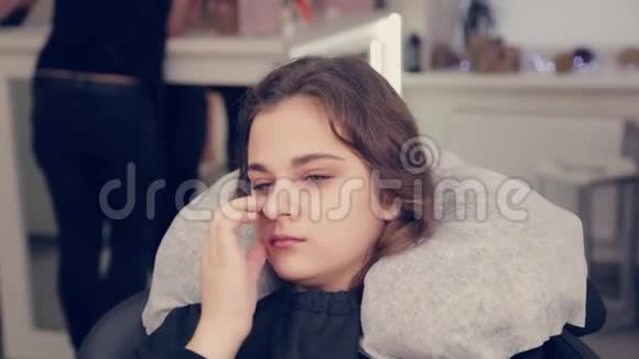 年轻的女孩在美容院的椅子上视频的预览图