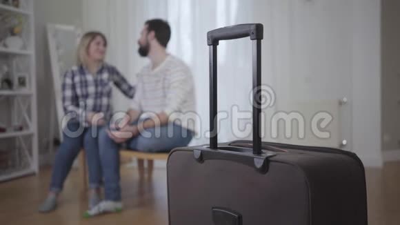 站在前台的手提箱的特写镜头就像幸福的年轻夫妇在后台拥抱一样已婚男女视频的预览图