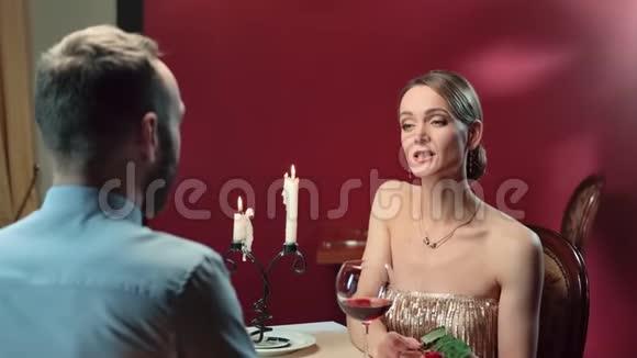 穿着晚礼服的性感女人微笑着和男人在晚餐约会时交谈4k龙红相机视频的预览图