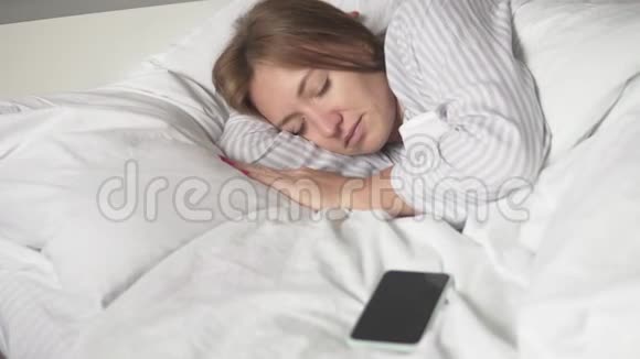 一个女人早上睡在床上她的手机响了视频的预览图