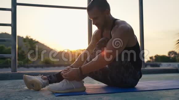 一个运动员坐在运动垫子上系鞋带视频的预览图