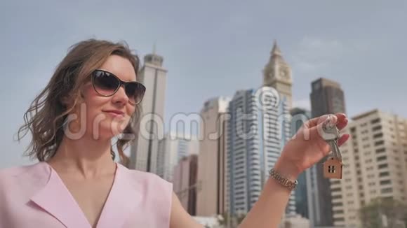 在迪拜摩天大楼里买公寓的概念那个女孩手里拿着新公寓的钥匙视频的预览图