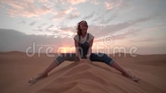 阿拉伯联合酋长国沙漠中的一个女孩在日落的背景下抛起了沙子视频的预览图