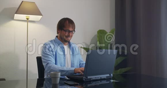 微笑的自由职业者使用笔记本电脑在家里上网工作视频的预览图