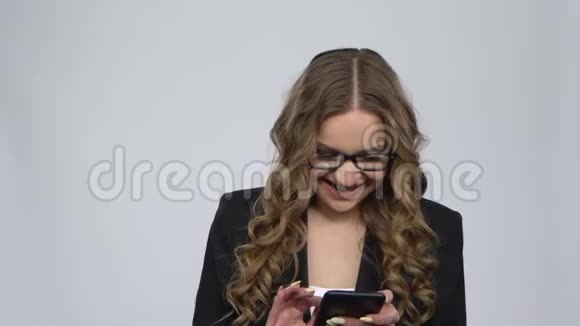 在录音室里一个快乐的女人在灰色背景下用手机发短信视频的预览图