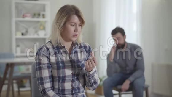 沮丧的白种人年轻女人看着手中的结婚戒指用手摸着脸丈夫压力过大视频的预览图