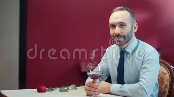 英俊的男性坐在桌子上酒和玫瑰等待的女性中型摄影机视频的预览图