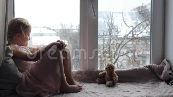 女孩坐在窗台上带着玩具熊微笑着视频的预览图