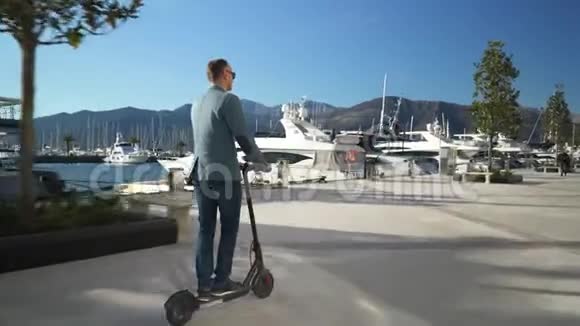 英俊的商人在游艇系泊中驾驶滑板车视频的预览图