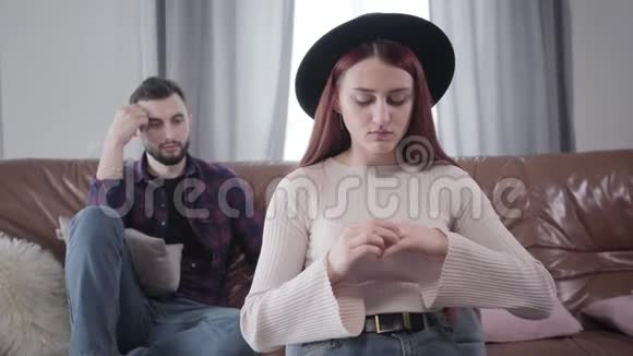 愤怒的高加索女人摘下结婚戒指她绝望的丈夫坐在后台年轻夫妇视频的预览图