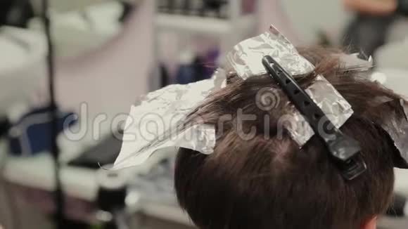 专业的理发师女染发女孩她的头发与染发箔视频的预览图