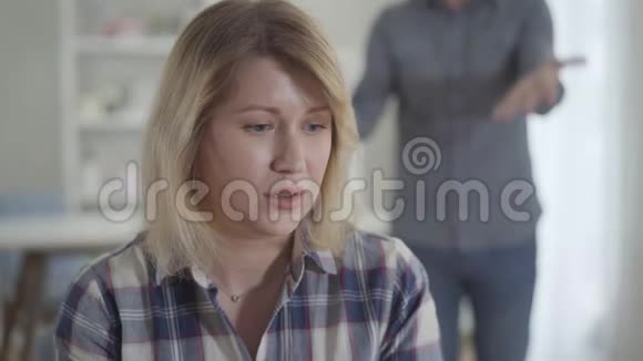 紧张的白人年轻女人的特写脸听着男人在后台大喊大叫沮丧的妻子与视频的预览图