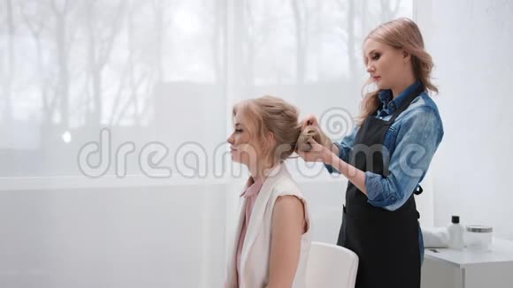 女理发师从女客户的时尚发型中拔出理发师中型摄影机视频的预览图