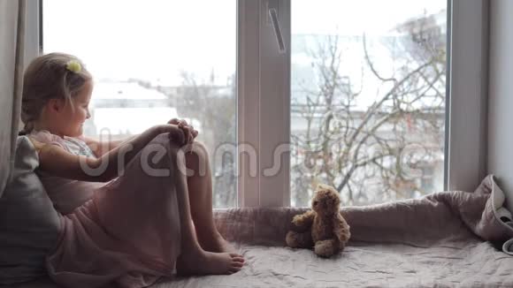 坐在窗台上的女孩带着一只泰迪熊视频的预览图
