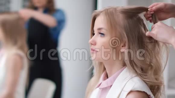 美发师将女性顾客编织波浪状头发的面部特写近距离拍摄4k红色相机视频的预览图