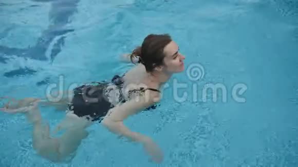 穿黑色泳衣的可爱女孩在游泳池里游泳视频的预览图
