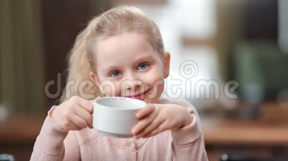 可爱的小女孩的脸拿着杯茶摆姿势在咖啡馆玩得很开心近距离拍摄4k红色摄像机视频的预览图