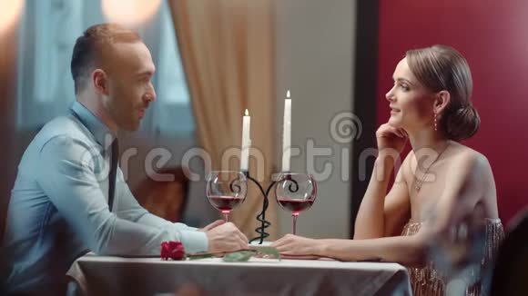 在浪漫的晚宴上穿着西装的微笑男人牵着优雅女人的手中型摄影机视频的预览图