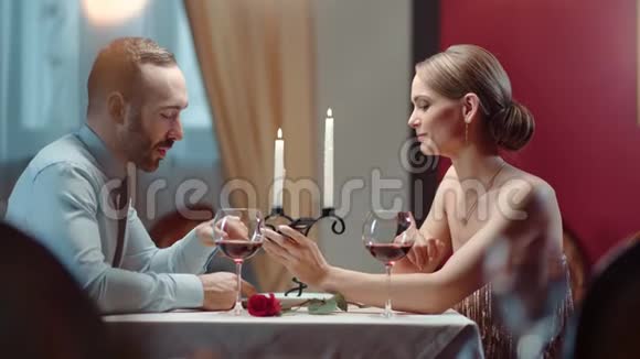 男女在餐厅的浪漫会议上讨论使用电话4k龙红相机视频的预览图