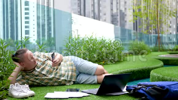 在草地上使用智能手机和平板电脑放松男性视频的预览图