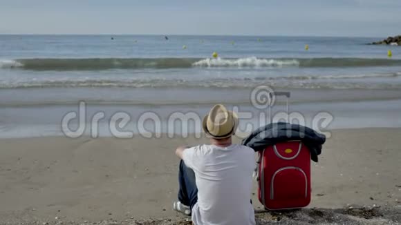 年轻的男游客坐在海滩上来休息视频的预览图