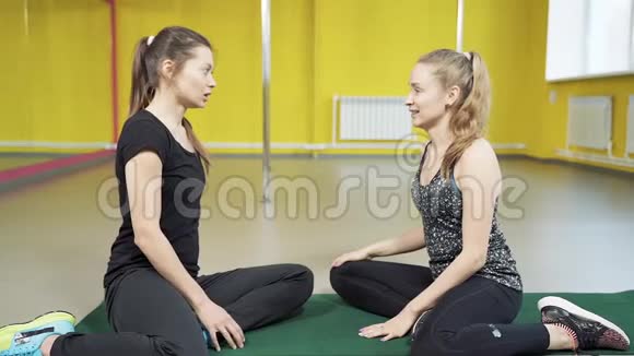 两个年轻的女朋友在工作室锻炼后微笑着交谈友谊积极的生活方式和运动理念视频的预览图