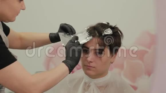 专业的理发师女染发女孩她的头发与染发箔视频的预览图