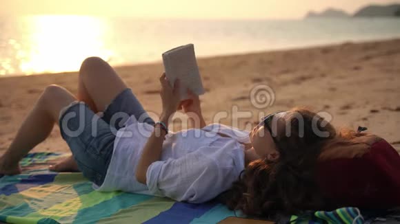 一个年轻的女人在海滩上看书放松视频的预览图
