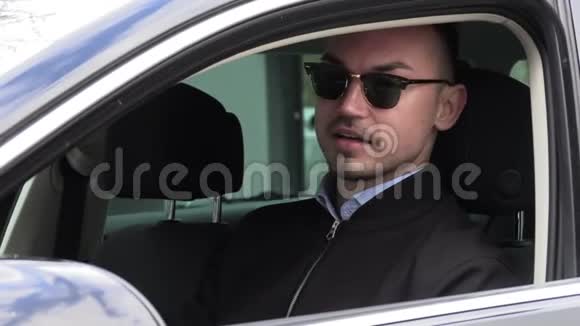 年轻时尚的男人戴着黑色太阳镜开车视频的预览图