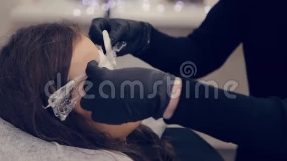 专业的女眉大师在一家美容院把眉毛上的胶卷放在眉毛上视频的预览图