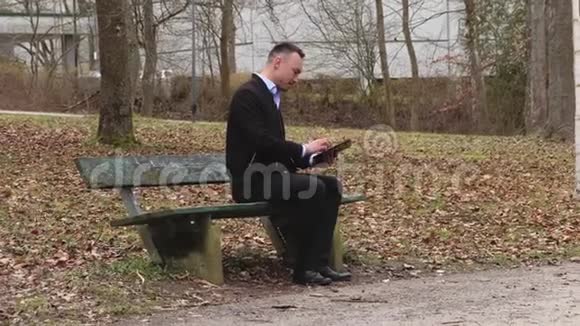 一个人独自在秋天的公园里坐在长凳上视频的预览图