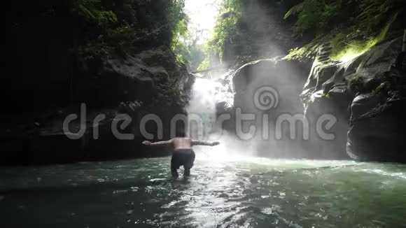 夏天高加索人在热带雨林瀑布中跳跃和游泳视频的预览图