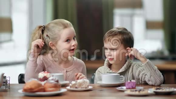 有趣的孩子男孩和女孩笑着吃甜点在咖啡馆喝茶4k龙红相机视频的预览图