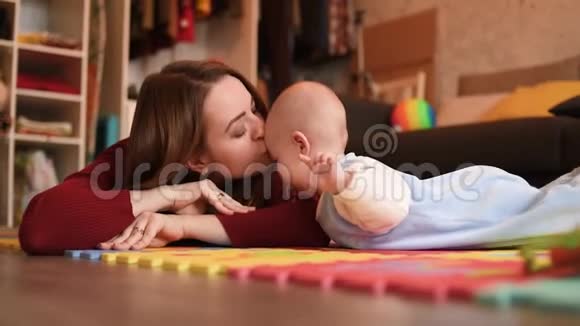 妈妈在公寓的地板上和孩子玩女人吻她的孩子视频的预览图