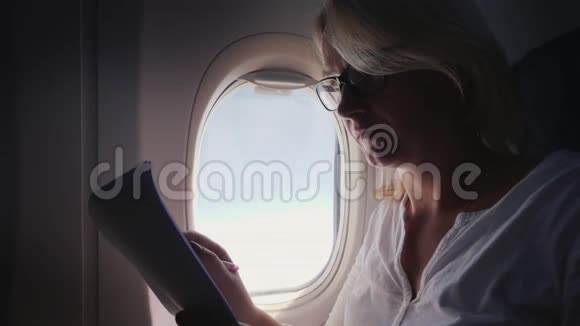 一个戴眼镜的年轻女子在飞机上看商业文件视频的预览图