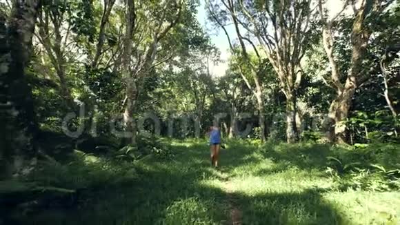 无忧无虑的年轻女子走在森林中央的绿色小路上视频的预览图