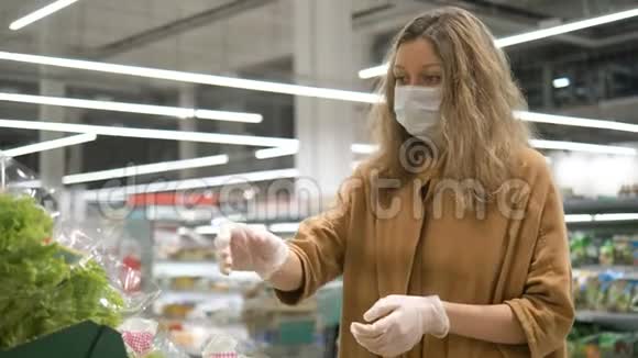 女人在超市里用医用口罩和橡胶手套选择新鲜沙拉保护儿童免受视频的预览图