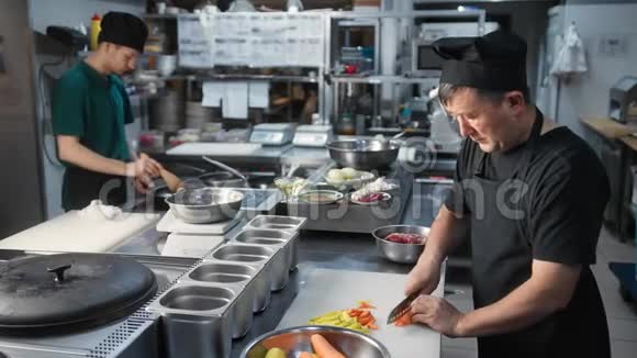 成熟的厨师在厨房用刀在船上切菜中型摄影机拍摄视频的预览图