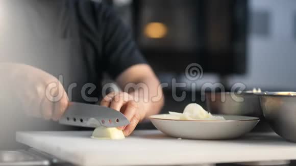 厨师员工用刀在桌板上切洋葱的特写4k龙红相机视频的预览图