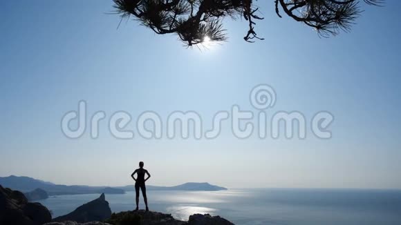 在克里米亚苏达克山上站着的运动少女的背影体育女游客剪影视频的预览图