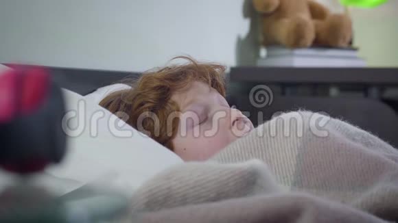 小红发白人男孩躲在毯子下的侧视吓坏了可爱的孩子害怕一个人压力视频的预览图