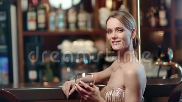 美丽的时尚女模特微笑着摆着酒在酒吧中型摄影机视频的预览图