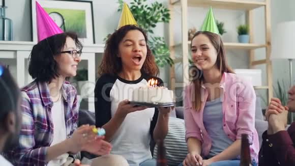 美国黑人妇女与朋友一起吹蜡烛生日蛋糕动作缓慢视频的预览图