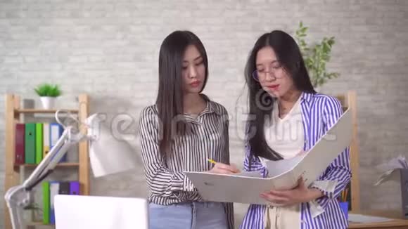 两名年轻的亚裔女职员讨论文件视频的预览图